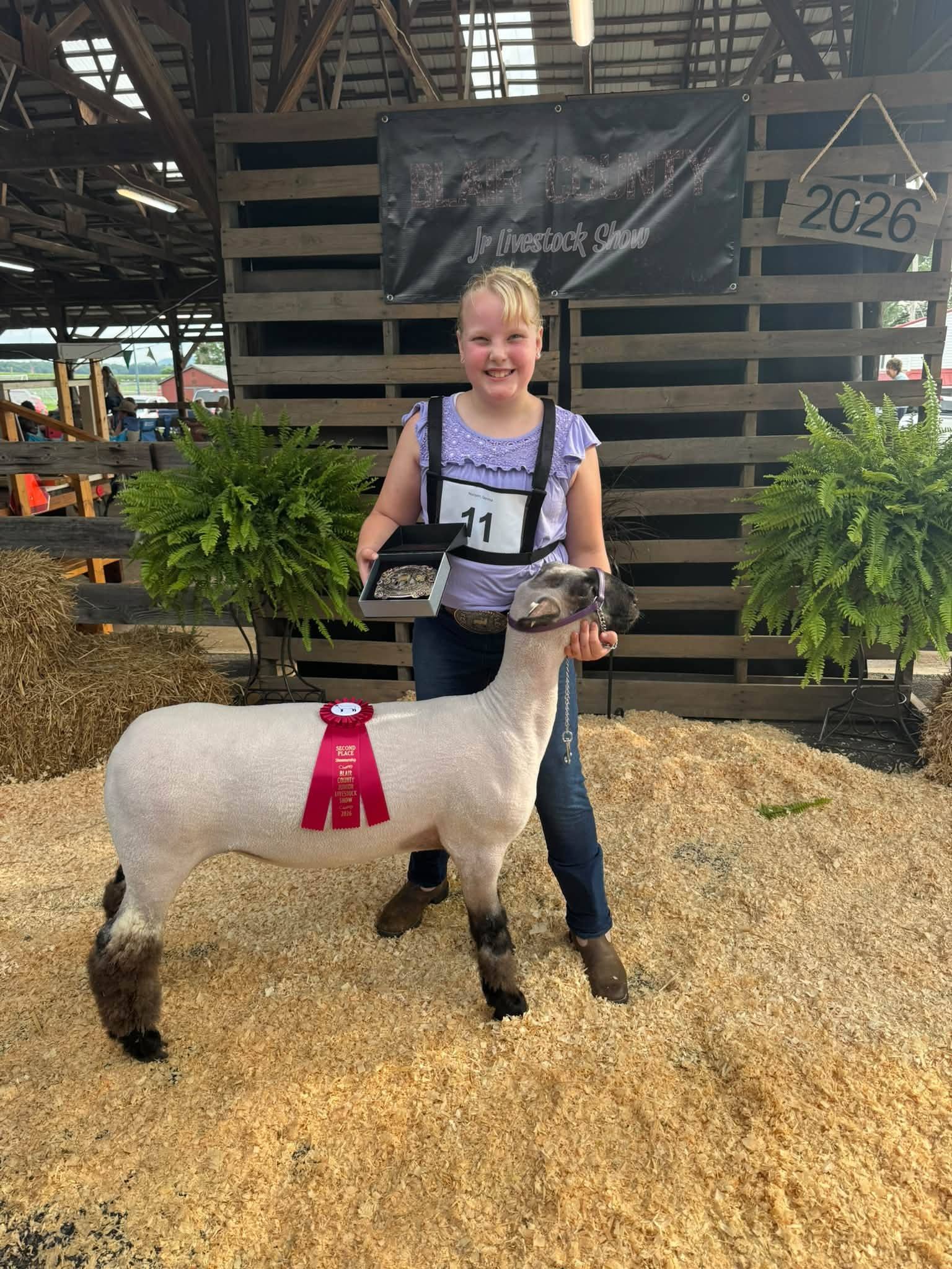 Gemma holding her lamb, which wears a red Reserve ribbon, at the 2026 Blair County Jr. Livestock Show